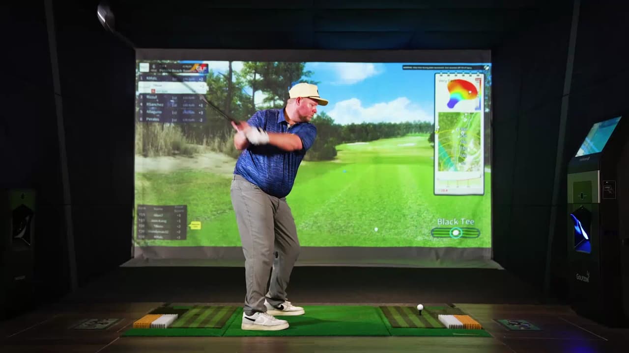 A player mid-swing in a bay, the Two Vision NX screen showing the hole and the shot data beside it.
